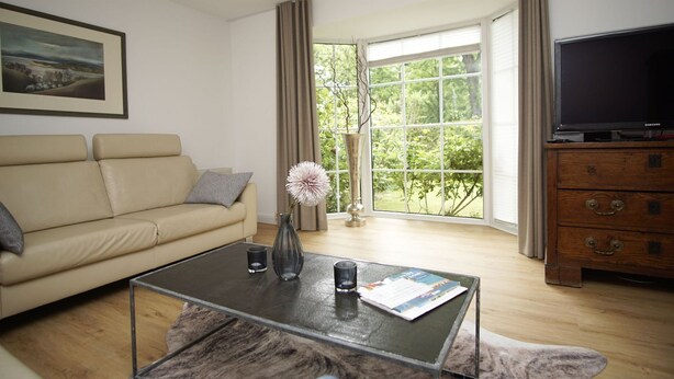 A living room with a sofa, coffee table, and a television. - Vacation home Wiking - in a quiet location, beautiful vacation home with terrace and garden (Binz)
