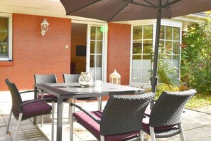 An outdoor patio with a table and chairs, a lantern, and a brick wall. - Vacation home Wiking - in a quiet location, beautiful vacation home with terrace and garden (Binz)
