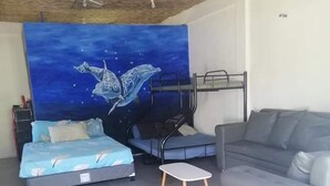 A bedroom with a bunk bed, a sofa, a small table, and a mural of a whale. - Anajawan Island Beachfront Resort  (General Luna)