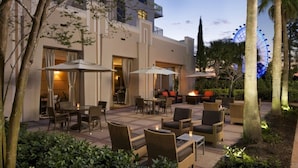 An outdoor patio with seating, a fire feature, and a Ferris wheel in the background. - Orlando | Resort Escape | Pool & Theme Parks Nearby (Orlando)