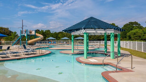 A swimming pool with multiple lanes, a water slide, and a gazebo.