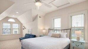 A bedroom with a bed, a nightstand, a chair, and a ceiling fan.