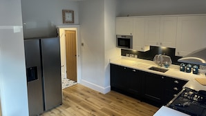 Una cocina moderna con electrodomésticos de acero inoxidable, gabinetes negros y una puerta de madera.