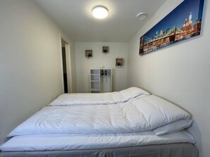 Une chambre à coucher avec un lit, une armoire et un tableau accroché au mur.