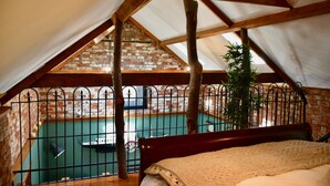 A bedroom with a view of a swimming pool, a wooden ceiling, and a brick wall. - 2-Bed 18th Century Barn - Sleeps 6 - Pet Friendly (Boston)