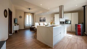 A modern kitchen with a central island, built-in appliances, and a dining area with a sofa and chairs. - Modern apartment in Gravedona- Larihome A14 (Gravedona ed Uniti)