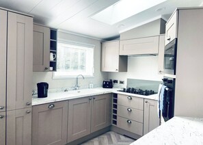 Una cocina moderna con ventana, armarios empotrados, un fregadero y una estufa.
