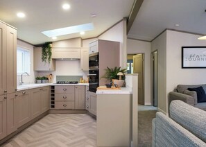 A compact kitchen with a herringbone floor pattern, built-in appliances, and a skylight.