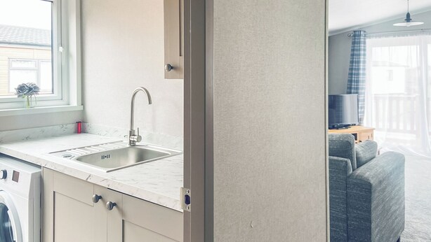 A modern kitchen with a sink, a window, and a washing machine.