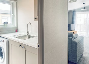 A modern kitchen with a sink, a window, and a washing machine.