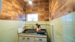 A compact kitchen with wooden walls, a window, and basic amenities. - SHATOREYOYOGI401 (Tokyo)