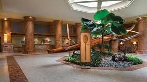 A lobby with a central plant, a slide, and a reception desk. - Kauai | Kauai Beach Escape | Pool & Beach (Kauai)