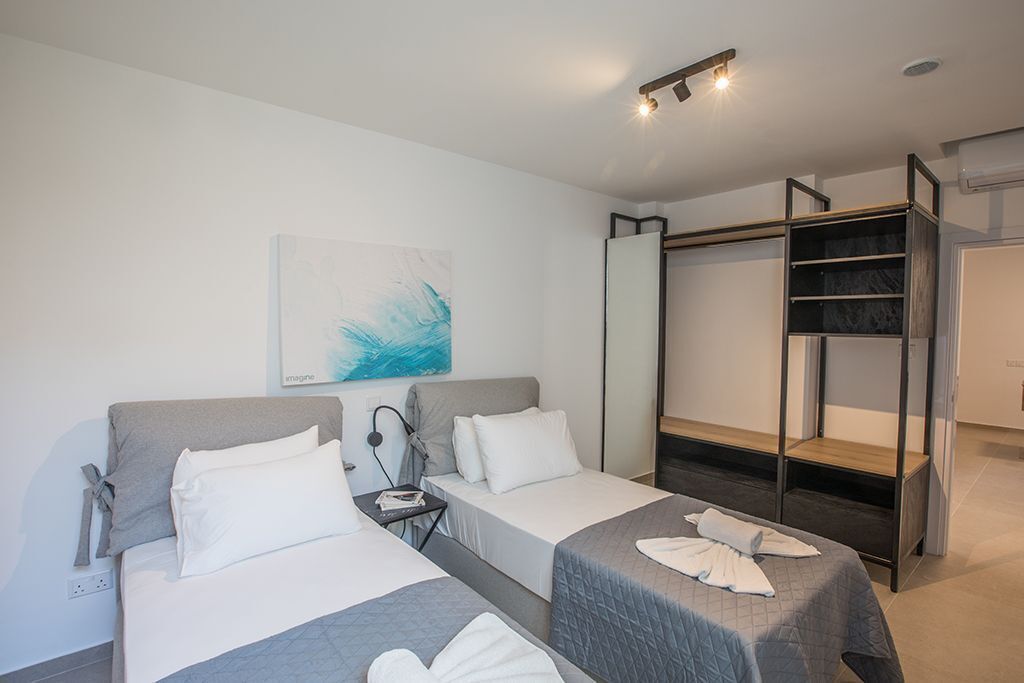 Ein Hotelzimmer mit zwei Betten, einem Schreibtisch, einem Spiegel und einem Kleiderschrank.