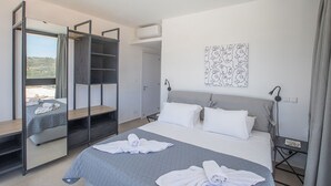 A modern hotel room with a large bed, a wardrobe with a mirror, a bedside table, and a wall art piece. - Protaras Elite Pearl Villa EP14 -  a villa that sleeps 11 guests  in 5 bedrooms (Protaras)