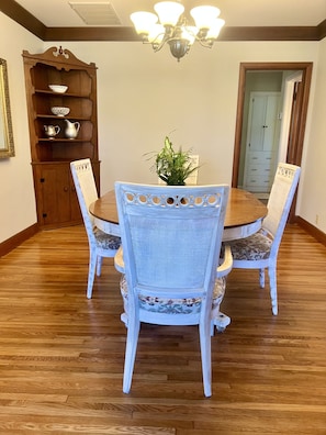 Enjoy meals in this dining area with a round table and four chairs, a chandelier, and a nearby cabinet.