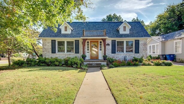 A two-story house with a stone facade, a front porch, and a small balcony. - Classy home w/ deck & fenced yard only 2 blocks from the fairgrounds!! (Tulsa)
