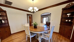 A dining room with a wooden table and chairs, a chandelier, and built-in wooden cabinets. - Classy home w/ deck & fenced yard only 2 blocks from the fairgrounds!! (Tulsa)
