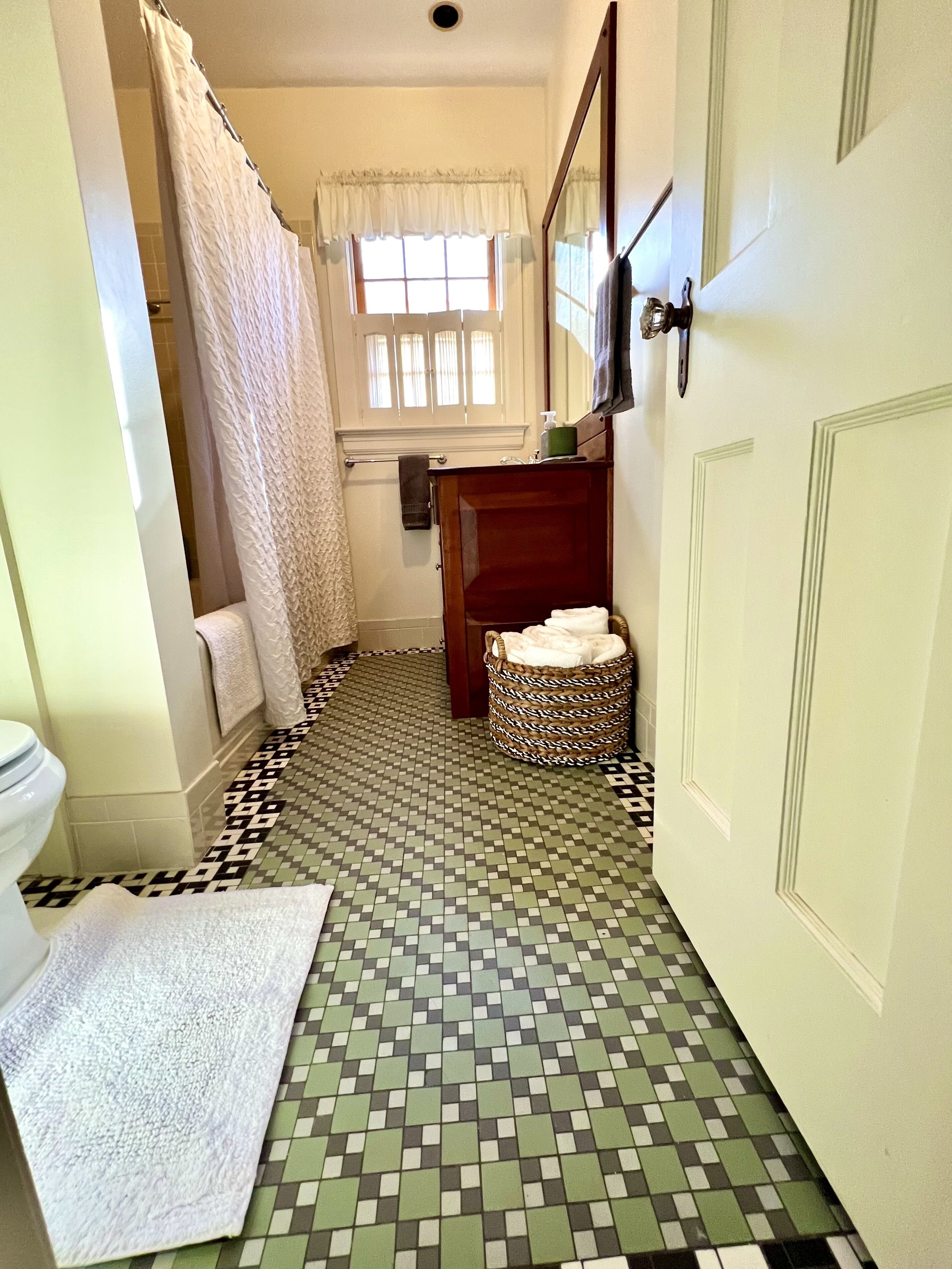 A bathroom with a tiled floor, a toilet, a sink, and a shower area.