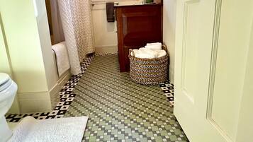 A bathroom with a tiled floor, a toilet, a sink, and a shower area.
