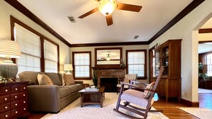 A living room with a ceiling fan, a fireplace, a rocking chair, and a sofa. - Classy home w/ deck & fenced yard only 2 blocks from the fairgrounds!! (Tulsa)