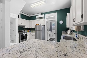 A modern kitchen with white cabinets, a stainless steel refrigerator, a built-in oven, and a granite countertop. - Art House Apt 1 Northend Historic Apartment (Boise)