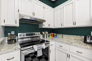 A kitchen with white cabinets, a stainless steel range, and a checkered floor.