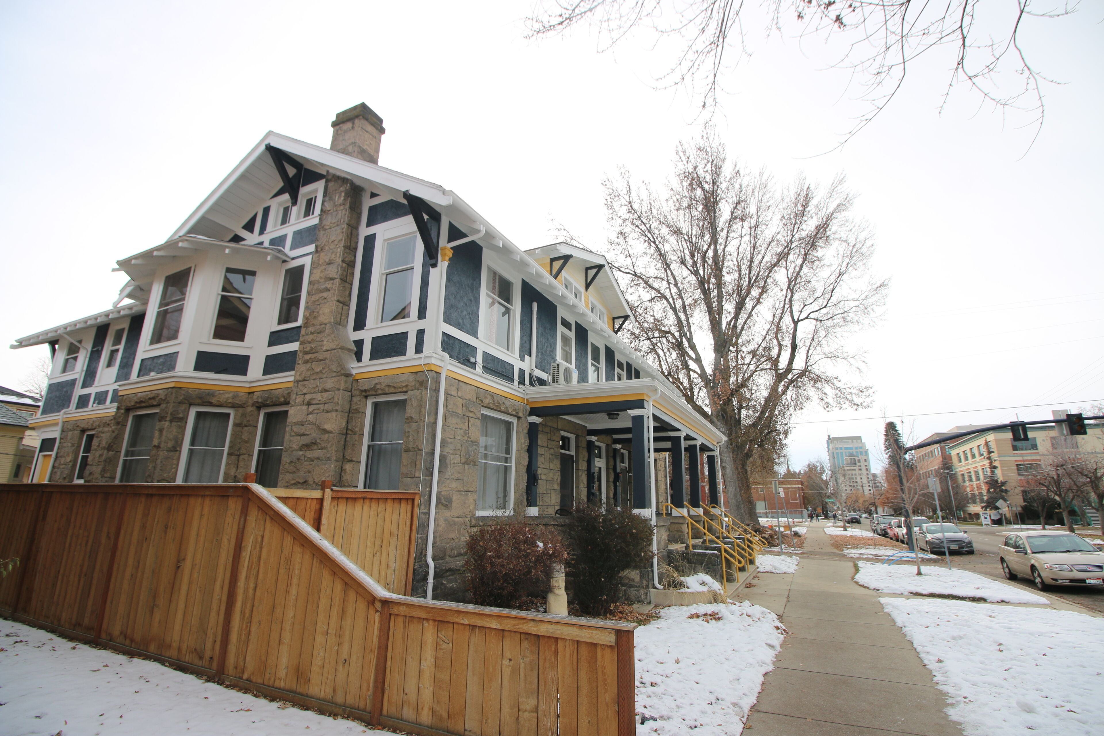 A multi-story house with a stone facade, large windows, and a wooden deck.