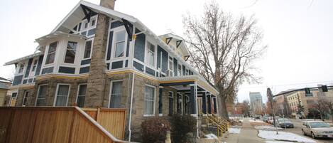 Une maison à plusieurs étages, dotée d’une façade en pierre, de grandes fenêtres et d’une terrasse en bois.