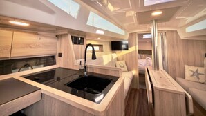 Ein kompaktes Wohnmobil-Interieur mit Küchenzeile, einer Sitzecke und Dachfenstern.