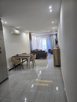 A modern living room with a dining area, a sofa, and a TV. - Jasmine Boutique Accommodation Felfela (Hurghada)