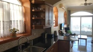 A kitchen with a sink, cabinets, and a window with curtains. There is a balcony with a view of the sea. - Sunny Seaside Retreat in Hurghada (Hurghada)