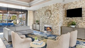 A modern lounge area with a fireplace, comfortable seating, and a large TV screen. - Palm Desert | Desert Oasis | Golf & Resort Pool (Palm Desert)