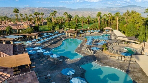 A resort with multiple swimming pools, sun umbrellas, and palm trees. - Palm Desert | Desert Oasis | Golf & Resort Pool (Palm Desert)