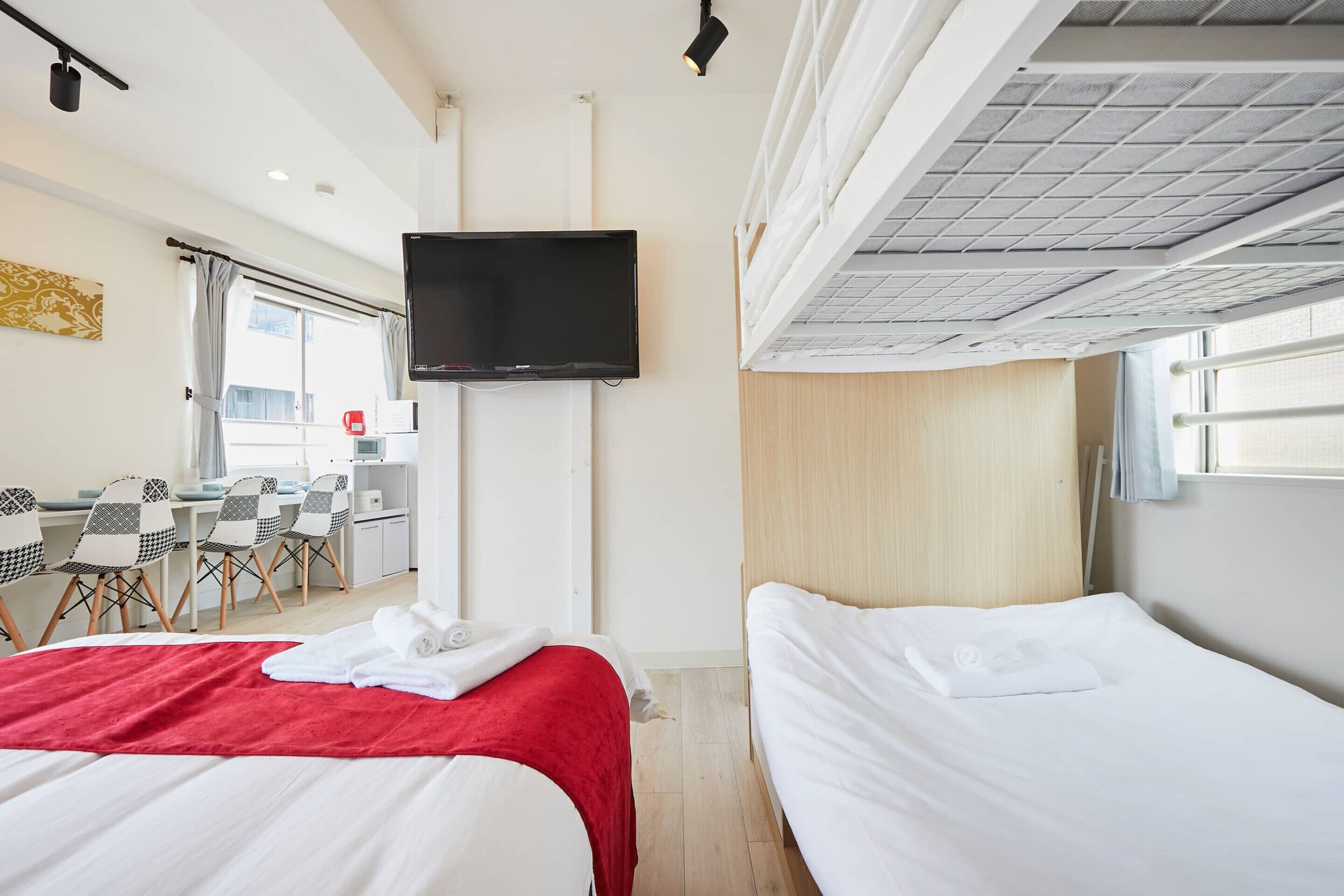 A hotel room with a bed, a desk with chairs, a television, and a window.