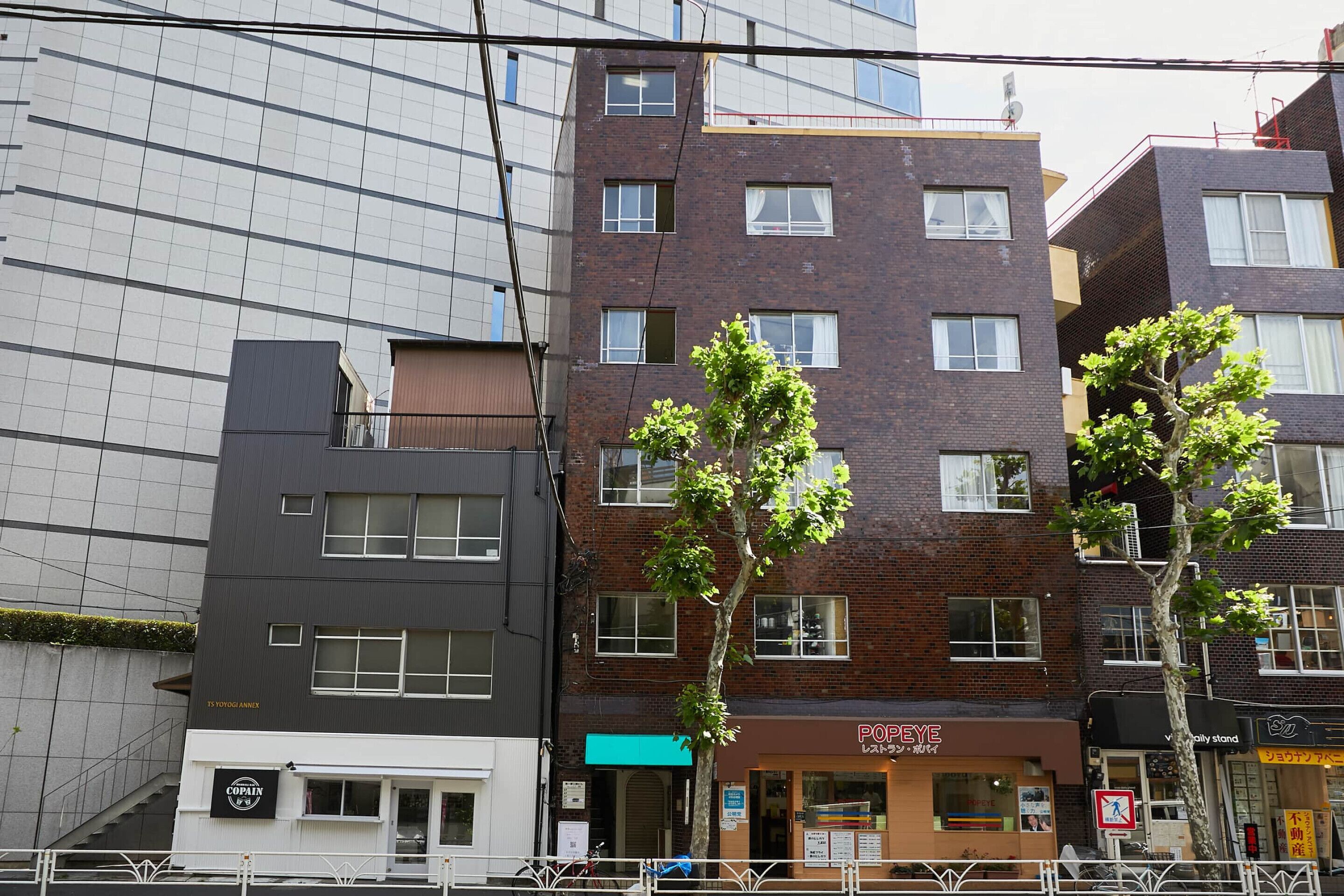 A multi-story building with various storefronts, including a visible restaurant named 'POPEYE.'
