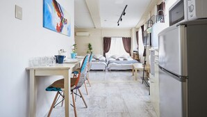 A modern kitchen with a refrigerator, microwave, and dining area with chairs and a table. - SHATOREYOYOGI (Tokyo)