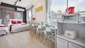A modern hotel room with a city view, a dining area with patterned chairs, a microwave, and a kettle on the counter. - SHATOREYOYOGI (Tokyo)