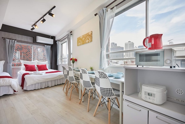A modern hotel room with a city view, a dining area with patterned chairs, a microwave, and a kettle on the counter. - SHATOREYOYOGI (Tokyo)