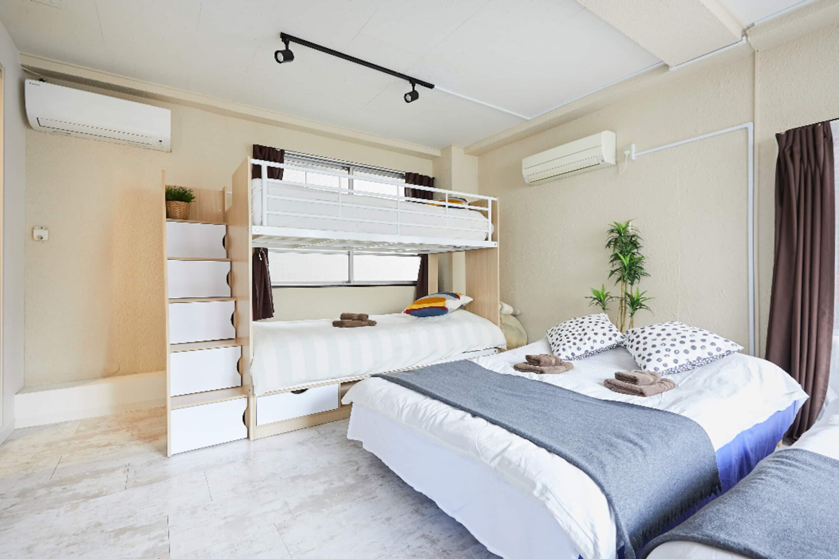 A bedroom with bunk beds, a desk, a chair, and a potted plant.