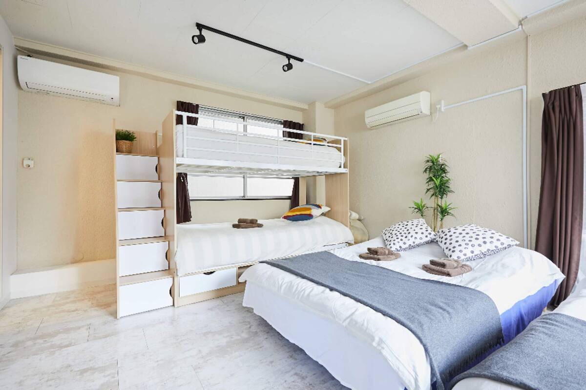 A bedroom with bunk beds, a desk, a chair, and a potted plant.