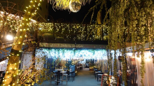 An outdoor dining area with string lights, tables, and chairs, under a covered section labeled 'Stella by Starlight.' - SHATOREYOYOGI (Tokyo)