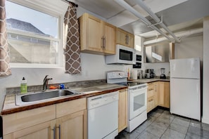 A kitchen with wooden cabinets, a dishwasher, a microwave, a stove, and a refrigerator.