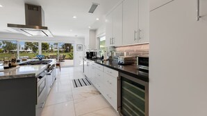 A modern kitchen with white cabinetry, stainless steel appliances, and a large island. - Fairway Luxe: New Remodel on Indian Canyons Course (Palm Springs)