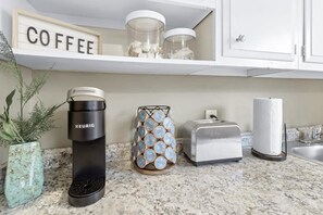 A kitchen counter with a Keurig coffee maker, a coffee container, a toaster, and a roll of paper towels. - Hillside Haven - affordable, and convenient (Chattanooga)