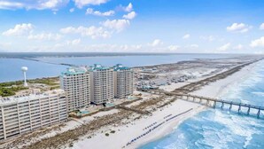 A coastal hotel with multiple high-rise buildings, a beach, and a pier extending into the water.