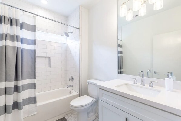 A modern bathroom with a bathtub, toilet, and a large mirror.