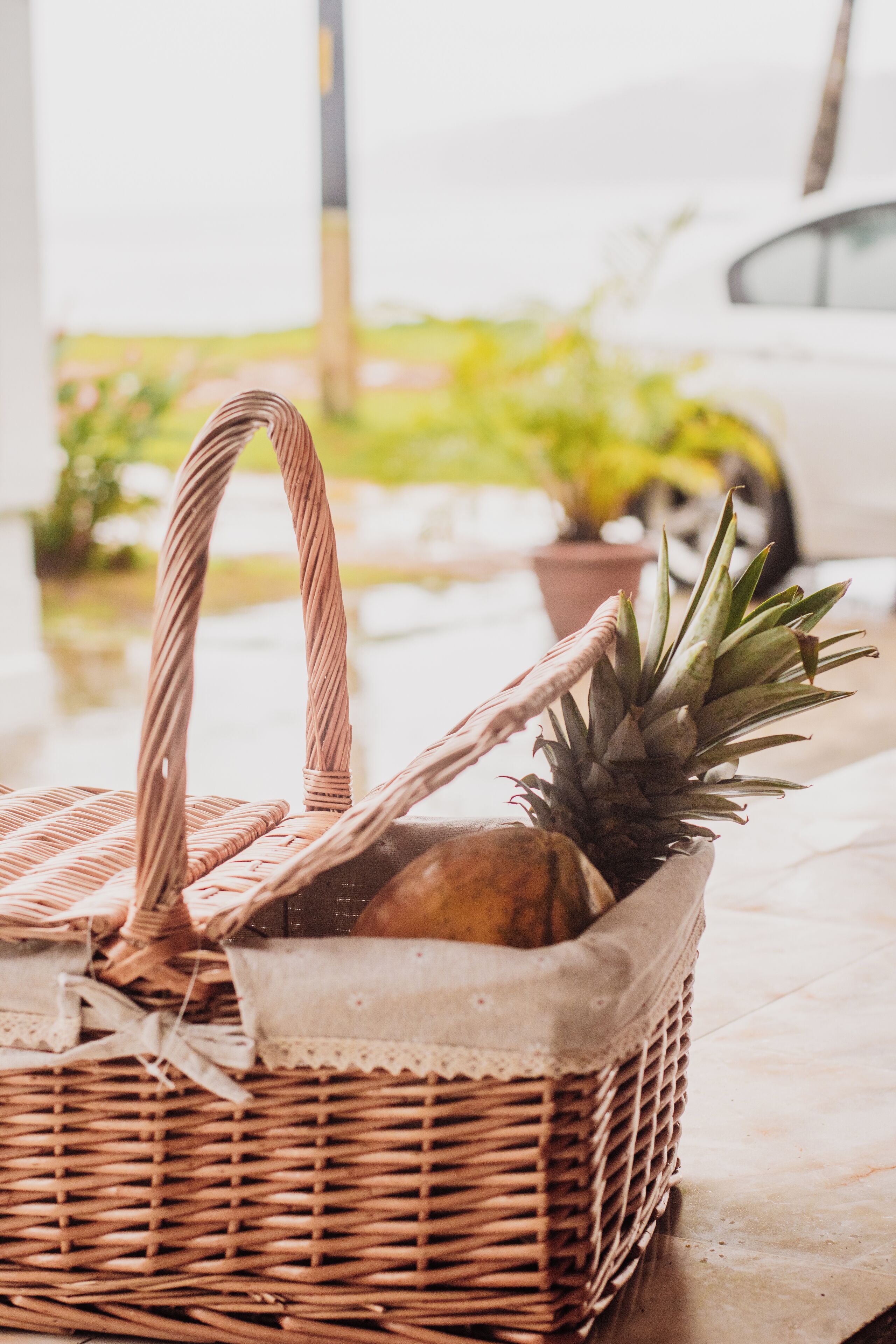 A wicker basket with a pineapple on a tiled floor.