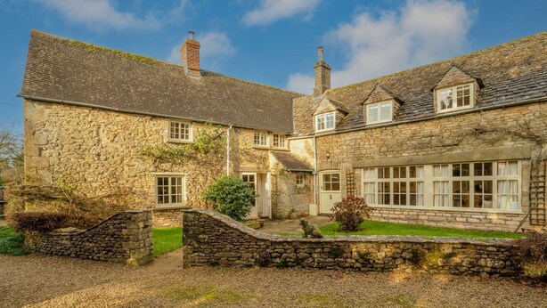 A stone building with a traditional design, featuring a central entrance, a small garden, and a stone wall. - Woodmancote Manor Cottage, near Cirencester - sleeps 6 guests in 3 bedrooms (Cirencester)