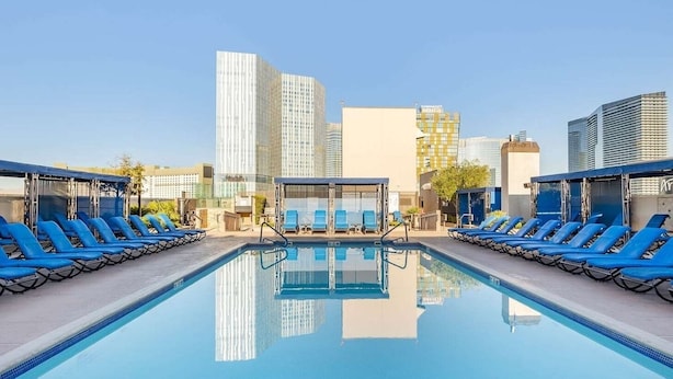 A rooftop pool with blue lounge chairs and a clear view of surrounding buildings.