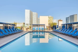 A rooftop pool with blue lounge chairs and a clear view of surrounding buildings.